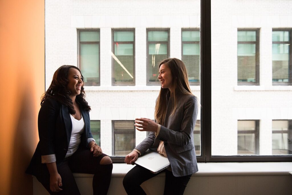 Two colleagues talking through a project by an office window